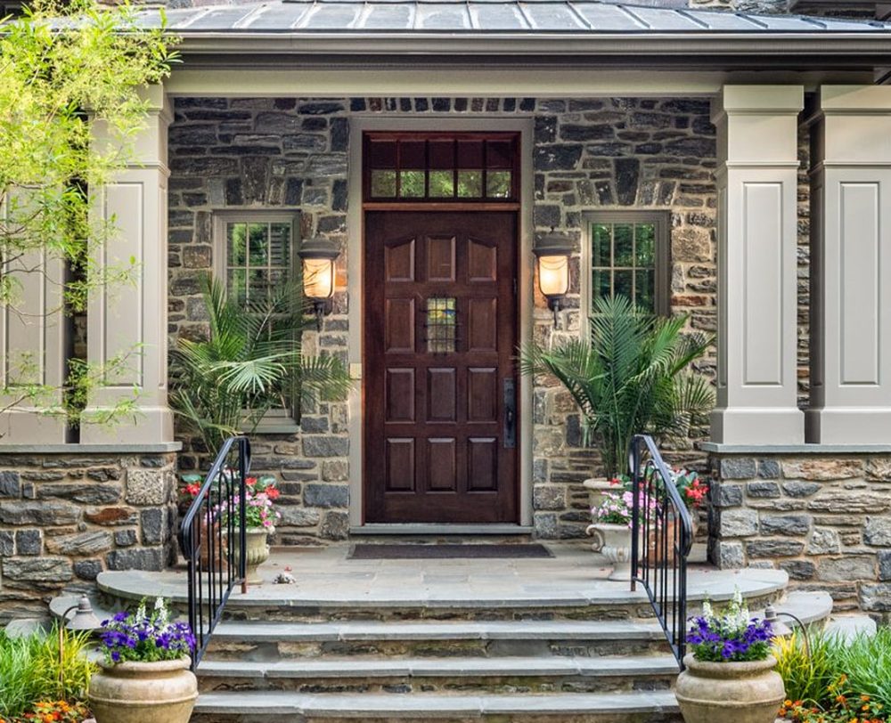 Stone porch with a mahogany front door, brass lanterns and bluestone steps
